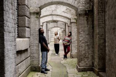 Evion Hackett, Angelica Brewster and Jade Hackett leaning against stone arches at Somerset House.