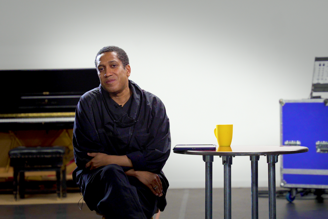 A still from Choreographer's Cut of Trajal Harrell sitting on a chair in a rehearsal studio.